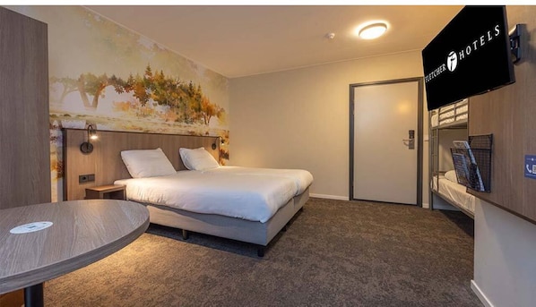 Een hotelkamer met een bed, een ronde tafel, een schilderij aan de muur en een televisie.