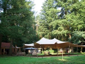 Un camping amb tòtems i un edifici petit, envoltat d'arbres.