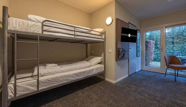 Een slaapkamer met stapelbedden, een televisie aan de muur en uitzicht op de omgeving door een glazen deur.