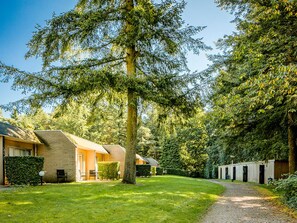 Een gebouw met meerdere kamers, een gazon en een pad dat naar een deur leidt.