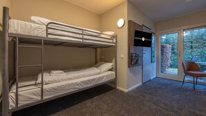 Une chambre avec des lits superposés, un téléviseur fixé au mur et une vue sur l’extérieur grâce à une porte vitrée.