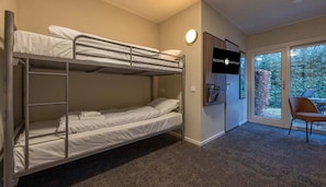 Une chambre avec des lits superposés, un téléviseur fixé au mur et une vue sur l’extérieur grâce à une porte vitrée.