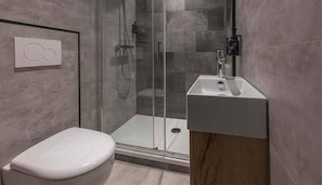 A modern bathroom with a glass shower enclosure, a white toilet, and a sink with a wooden vanity. - Charming Room in the Woods – Ideal for Couples' Getaway (Putten)