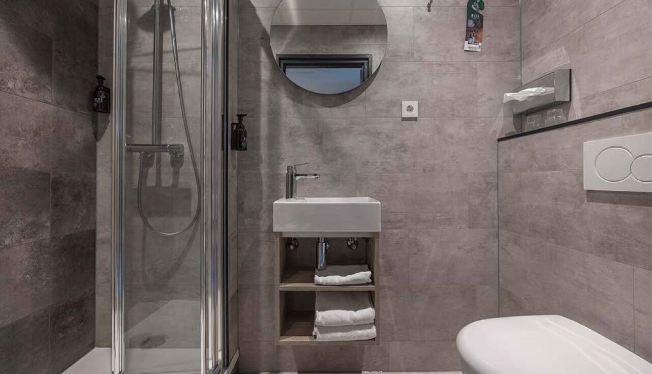Un baño moderno con ducha envuelta en vidrio, lavamanos con espejo y retrete.