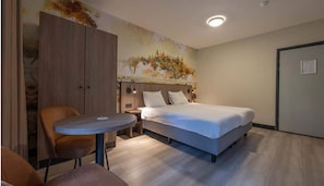 Een slaapkamer met een bed, een tafel en een stoel.