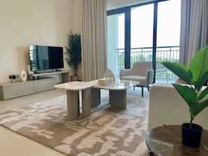 A modern living room with a flat-screen TV, a coffee table, a sofa, and a potted plant. - Serene Yas Island Hideaway w Resort Facilities (Abu Dhabi)