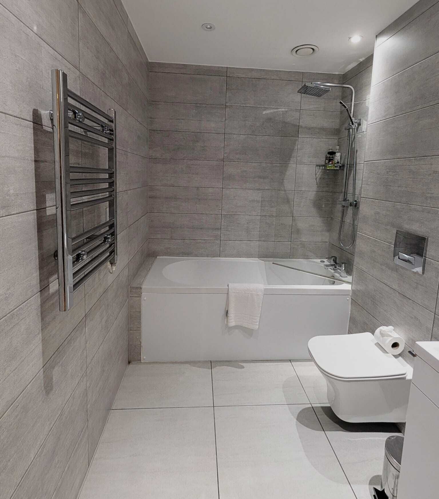 A modern bathroom with a bathtub, toilet, and shower.