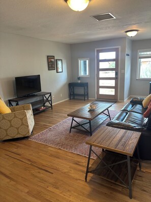 A living room with a sofa, a coffee table, a TV, and a door leading outside. - Lovely updated 3-bedroom house in quaint Cortez perfect for your getaway (Cortez)