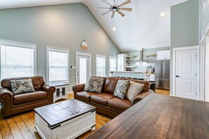 A living room with a brown leather sofa, a wooden coffee table, and a ceiling fan.