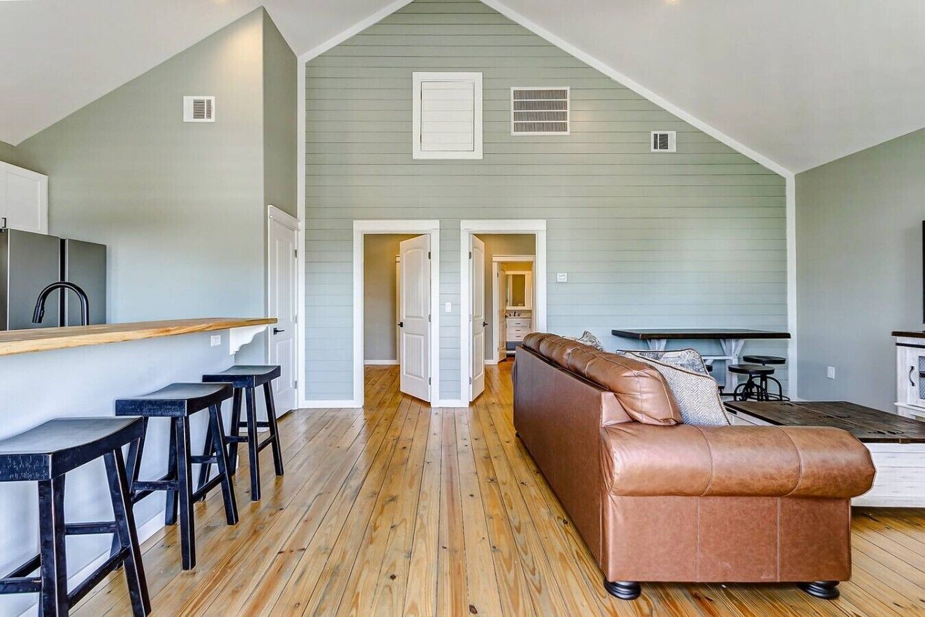 Un loft amplio con área de cocina, comedor y sala de estar con sofá de cuero marrón.
