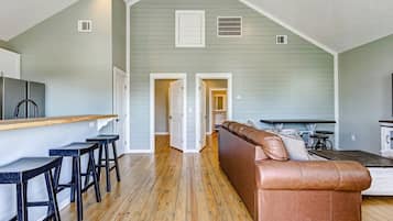 Un loft amplio con área de cocina, comedor y sala de estar con sofá de cuero marrón.