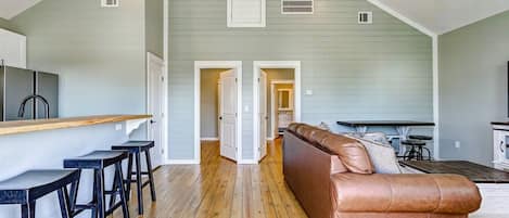A spacious loft with a kitchen area, a dining space, and a living room with a brown leather sofa.