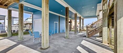 Ein überdachter Außenbereich mit Betonböden, Holzsäulen und einer blauen Decke.