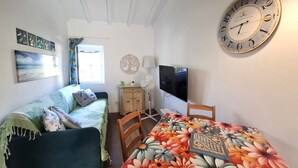 Ein Zimmer mit einem Bett, einem Tisch mit Blumenmuster, einer Uhr und einem Fernseher.