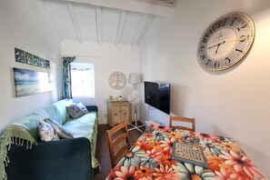 Ein Zimmer mit einem Bett, einem Tisch mit Blumenmuster, einer Uhr und einem Fernseher.
