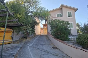 A pathway leading to a building with a balcony and a door. - Sighello Apartment (La Pila)