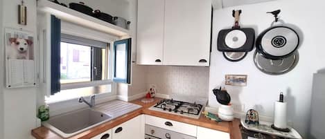 Una cocina compacta con lavamanos, estufa, horno y una ventana con cortinas.