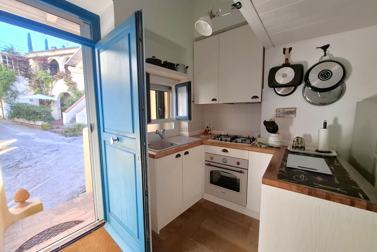 Una cocina con gabinetes blancos, una estufa a gas, un fregadero y una ventana.