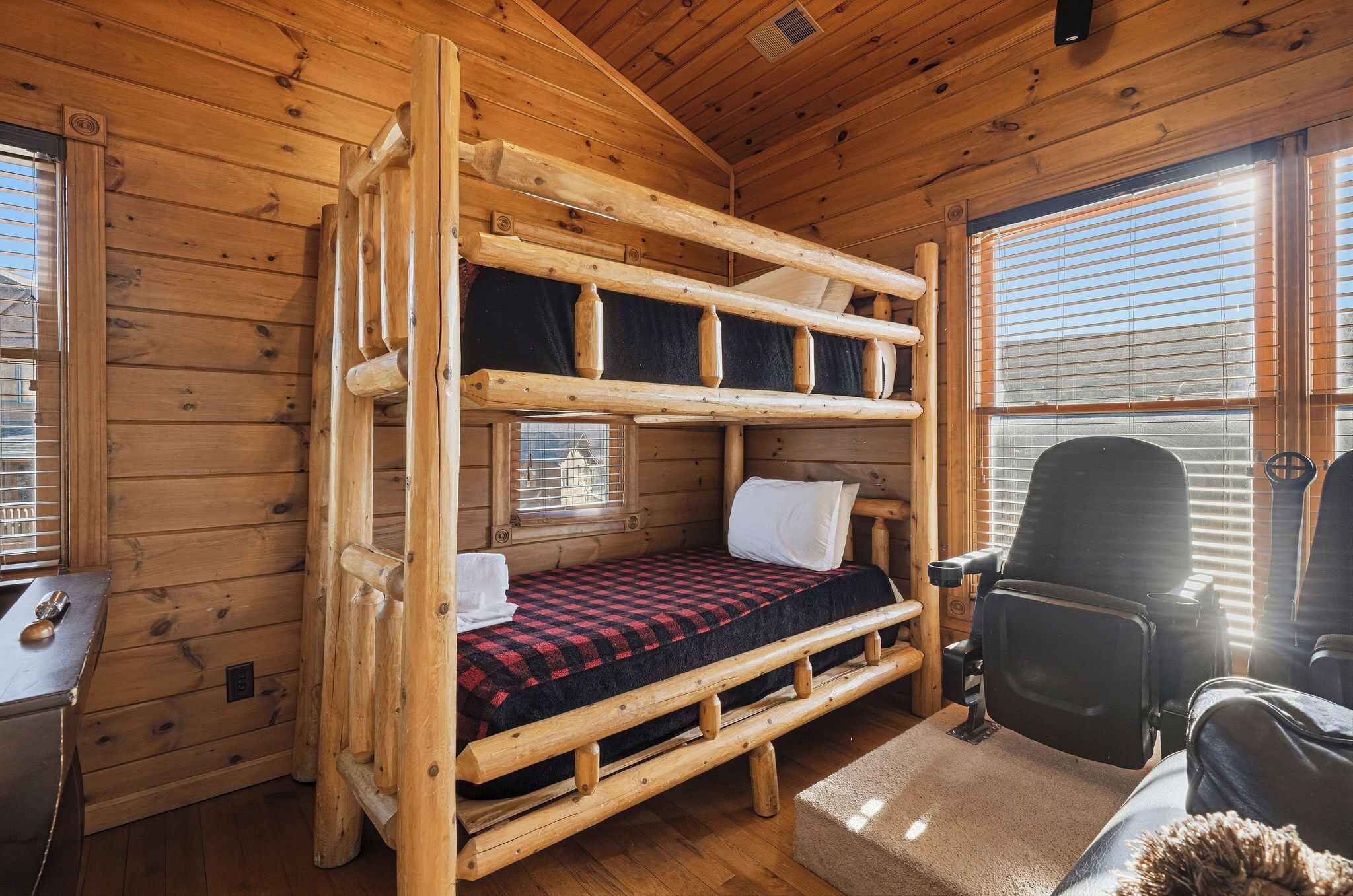 Interior de una cabaña de madera con una litera, un escritorio y una silla.