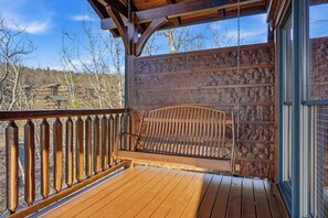 Eine Holzterrasse mit Schaukelstuhl, Holzgeländer und Blick auf eine Berglandschaft.