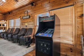 Eine Reihe von Gaming-Stühlen und ein Multicade-Spielautomat in einem Holzraum mit Jalousien.