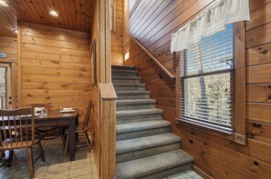 A wooden interior with a staircase, a dining area, and a window with blinds. - Mountain Movie Night in Gatlinburg (Gatlinburg)