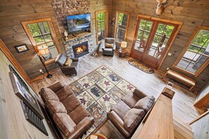 A cozy cabin interior with a fireplace, leather sofa, and a television. - Modern Rustic Charm in Pigeon Forge (Sevierville)