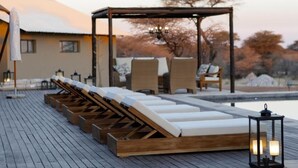 Zona de piscina con sillones de descanso y una pérgola.