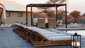 Ein Poolbereich mit Liegestühlen und einer Pergola.