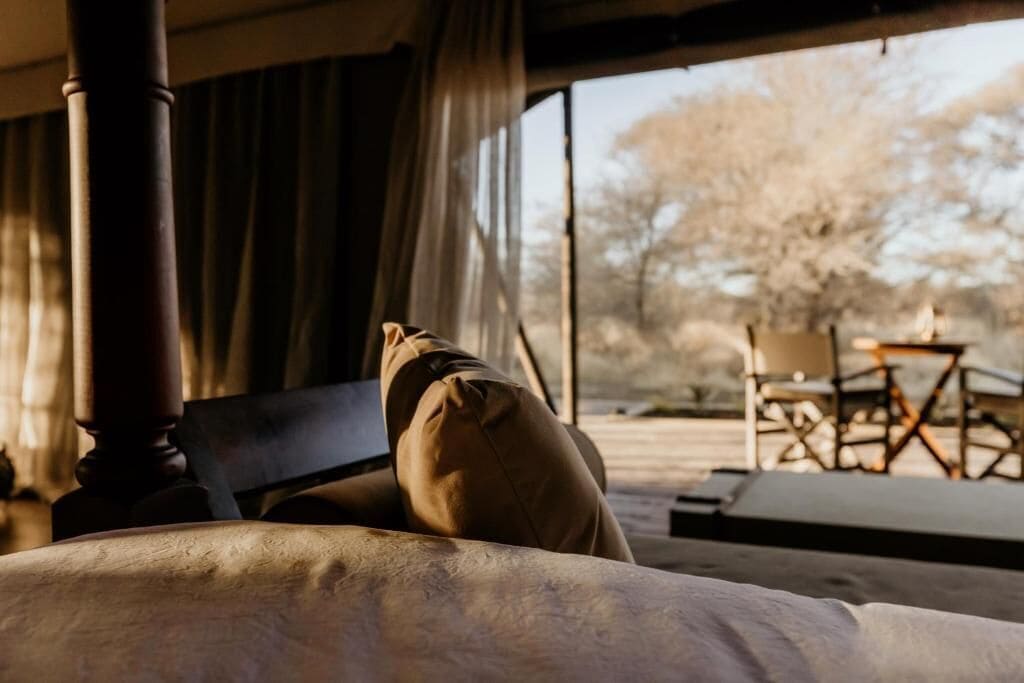 Ein Zimmer mit einem Bett, einem Sessel und Blick ins Freie.