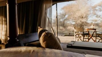 Ein Zimmer mit einem Bett, einem Sessel und Blick ins Freie.