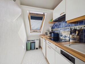 Une cuisine compacte dotée d’une lucarne, d’un four à micro-ondes, d’un grille-pain et d’un lave-vaisselle.