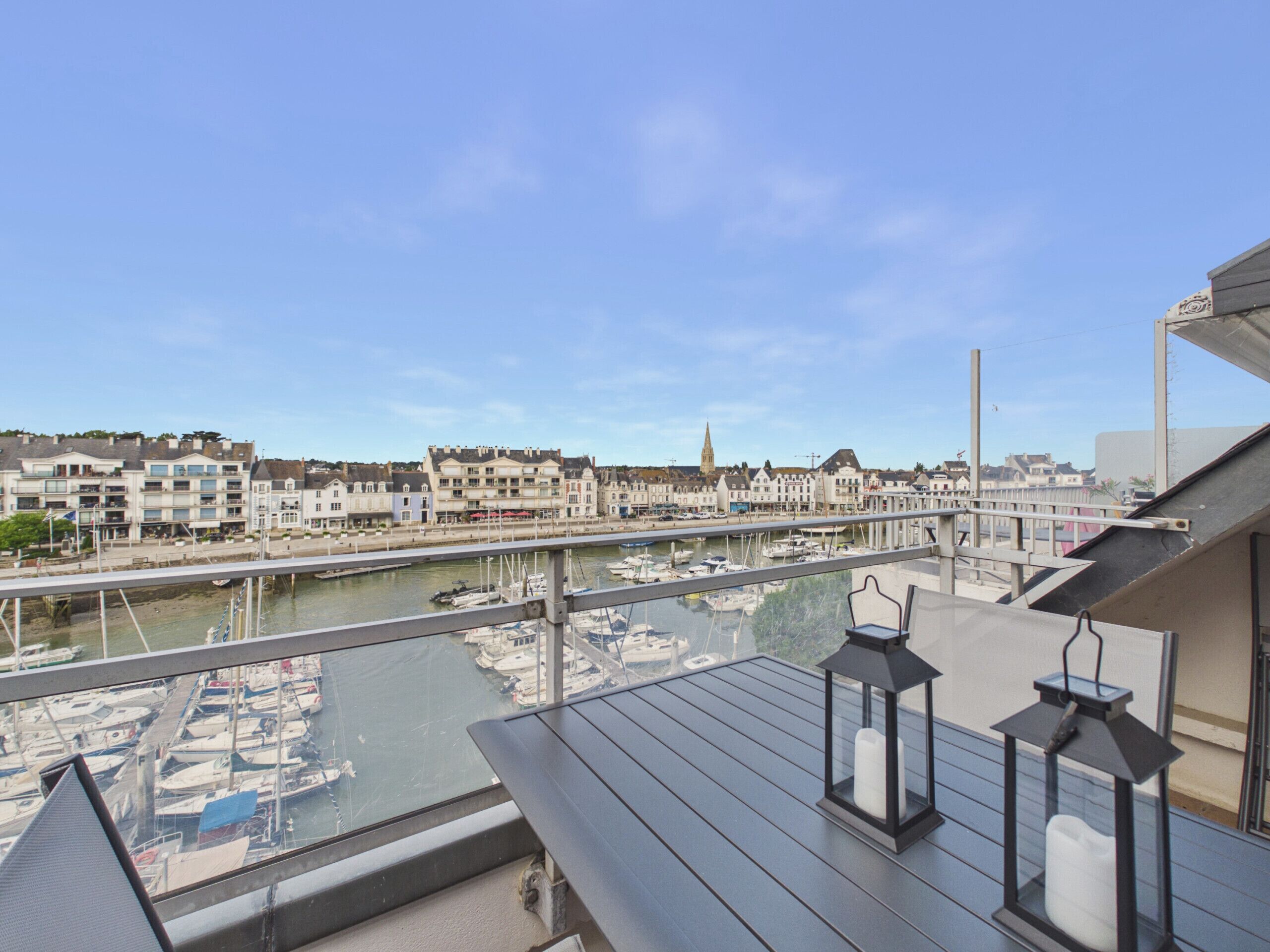 A balcony with a view of a marina and buildings across the water.