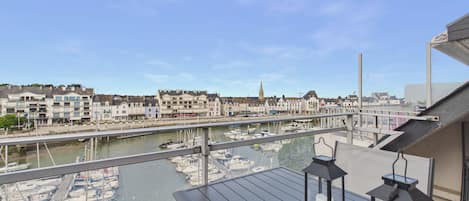 A balcony with a view of a marina and buildings across the water.