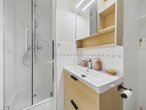 Ein modernes Badezimmer mit Glasdusche, Waschbecken mit Holdekor und Spiegel darüber.