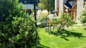 Un jardín bien cuidado con un camino que lleva a un edificio de paredes de piedra y techo de metal.