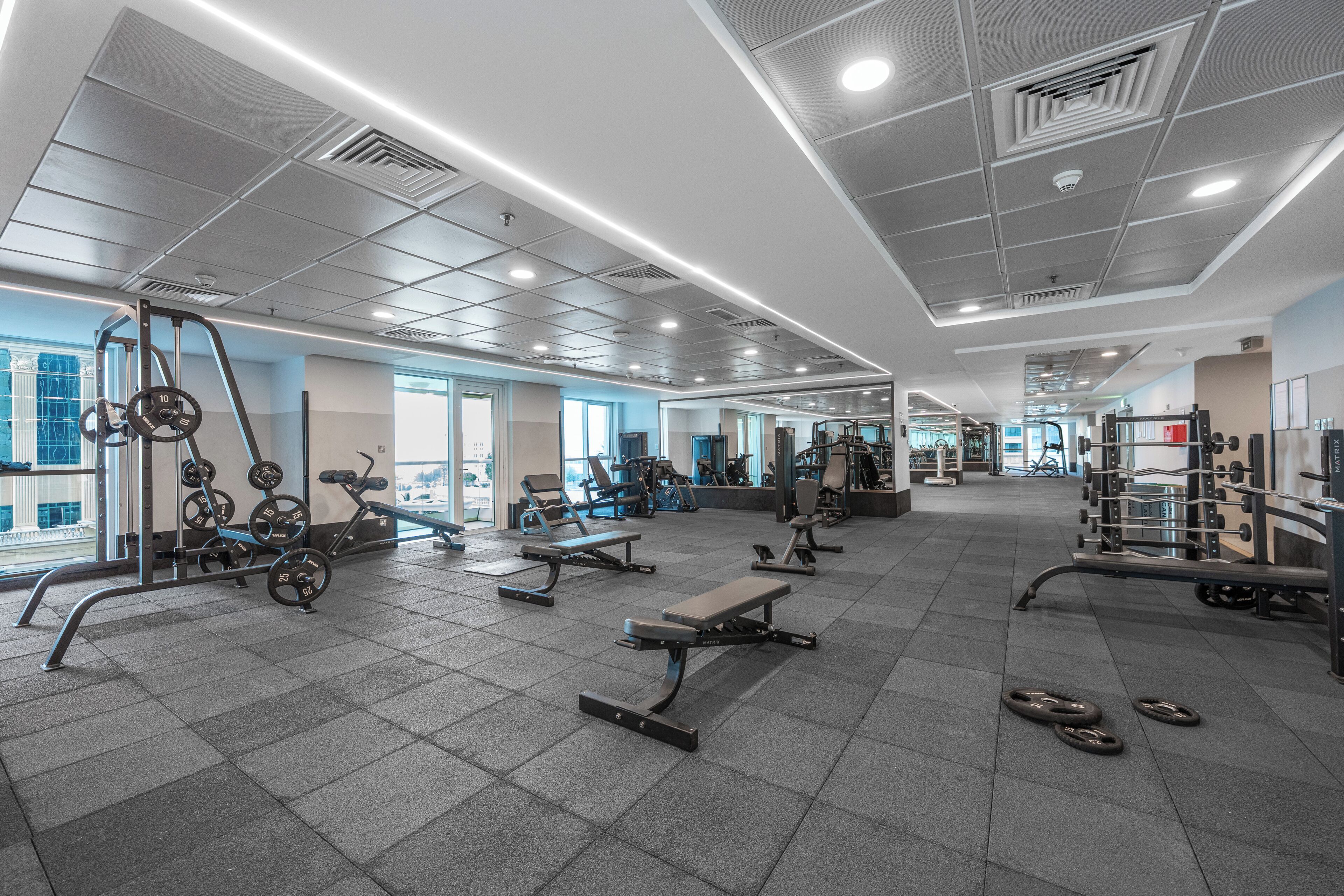 A gym with various exercise equipment, including weight machines and free weights, and a spacious layout.
