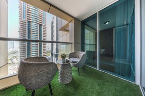 A balcony with two wicker chairs, a small table, and a potted plant. - StayShort - Comfortable 1 bedroom in Marina with Balcony! (Dubai Marina)