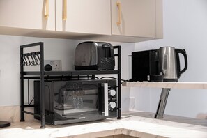 Une cuisine équipée d’un four à micro-ondes, d’un grille-pain et d’une machine à café, le tout posé sur un plan de travail.
