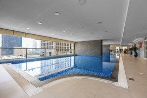 Una piscina interna moderna con una vista chiara sullo skyline cittadino attraverso ampie finestre.