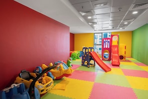 Un espace de jeux pour enfants avec des tapis colorés, des structures de jeu et des jouets.