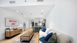 A modern living room with a sofa, coffee table, and a kitchen area in the background.
