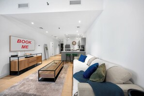 A modern living room with a sofa, coffee table, and a kitchen area in the background.