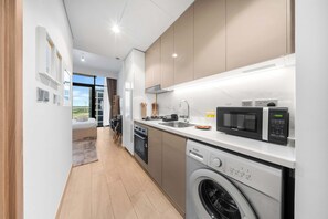 A modern kitchen with a built-in oven, microwave, and dishwasher. - StayShort - Luxury Studio Apartment in Meydan with Balcony (Meydan)