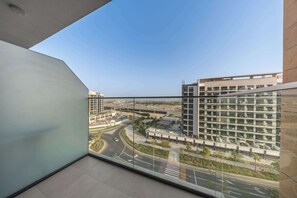 A balcony with a view of a modern building complex and a road. - StayShort - Luxury Studio Apartment in Meydan with Balcony (Meydan)