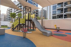 Ein Kinderspielbereich mit Rutsche, Klettergerüst und Schaukeln.