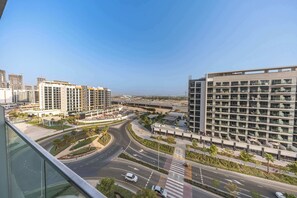 A modern urban landscape with high-rise buildings, a curved road, and a clear sky. - StayShort - Luxury Studio Apartment in Meydan with Balcony (Meydan)