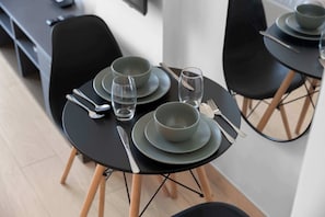 Een eettafel gedekt met borden, kommen, bestek en glazen, omringd door stoelen.
