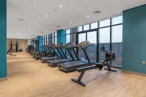 Een fitnessruimte met loopbanden, trainingsfietsen en krachtapparaten.