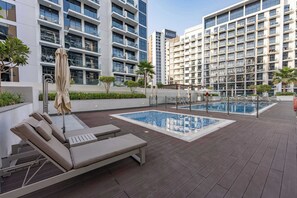 A rooftop pool area with lounge chairs and a swimming pool. - StayShort - Luxury Studio Apartment in Meydan with Balcony (Meydan)